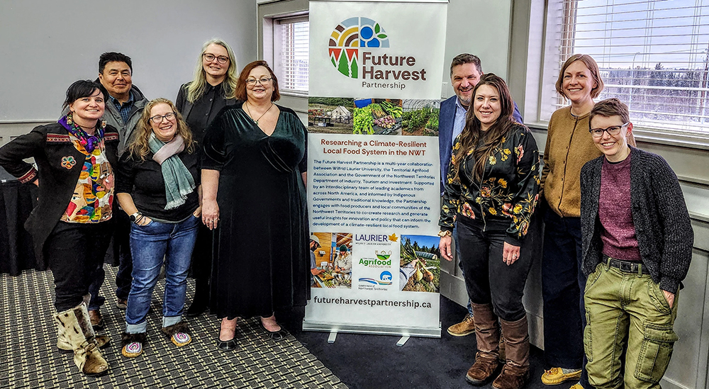 FHP@GROW people standing in a conference room surrounding a banner with Future Harvest Partnership information